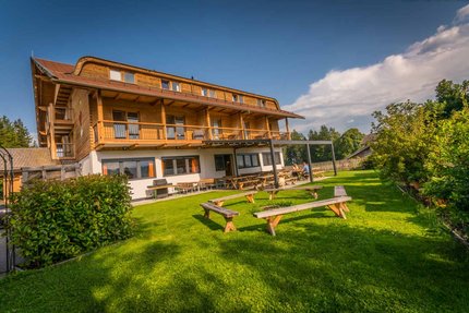Hotel Gasthof Deixelberger © Moppetfoto.de Houten huis met terras en bankjes op groen gras onder blauwe lucht