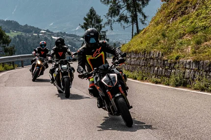Trentino © Andrea Acler Drei Motorräder fahren auf einer bergigen Straße mit Fahrern in Schutzkleidung