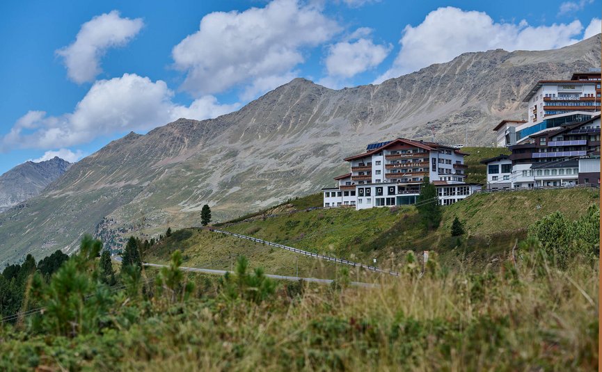 Alpenhotel Laurin ***S © studio22.at - Marcel Hagen Alpenhotel am Hang mit Bergpanorama unter blauem Himmel