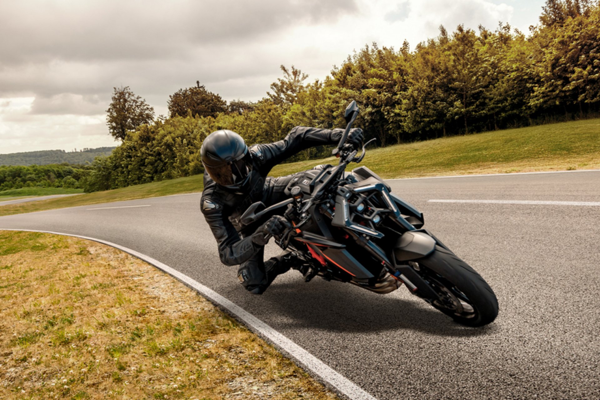 Motorvakantie © Continental Motorcoureur in zwarte uitrusting leunt in een bocht op een kronkelende weg