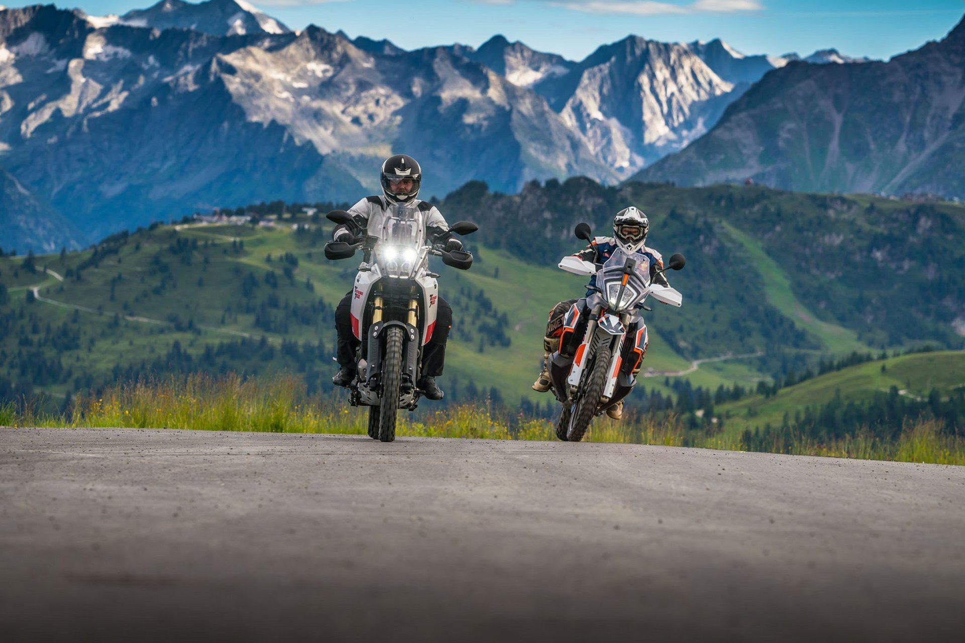 Motorvakantie Twee motorrijders op bergweg met Alpen op de achtergrond