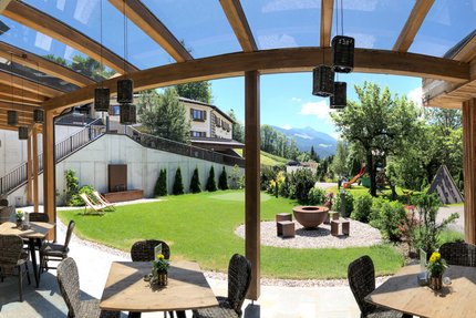 Landhotel & Gasthof Laudersbach © Manuel Jäger Überdachte Terrasse mit Tischen, Stühlen und Bergblick in einem Garten