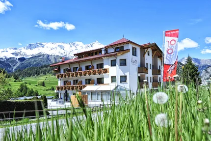 Alpen Boutique Hotel Alpetta Hotel in de Alpen met besneeuwde bergen en groen gras op de voorgrond