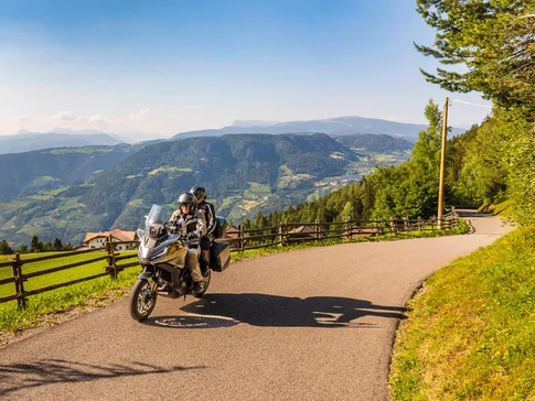 Val d'Ega - Carezza meer © Alexander Seger Twee motorrijders op bergweg met uitzicht op groene valleien en heuvels