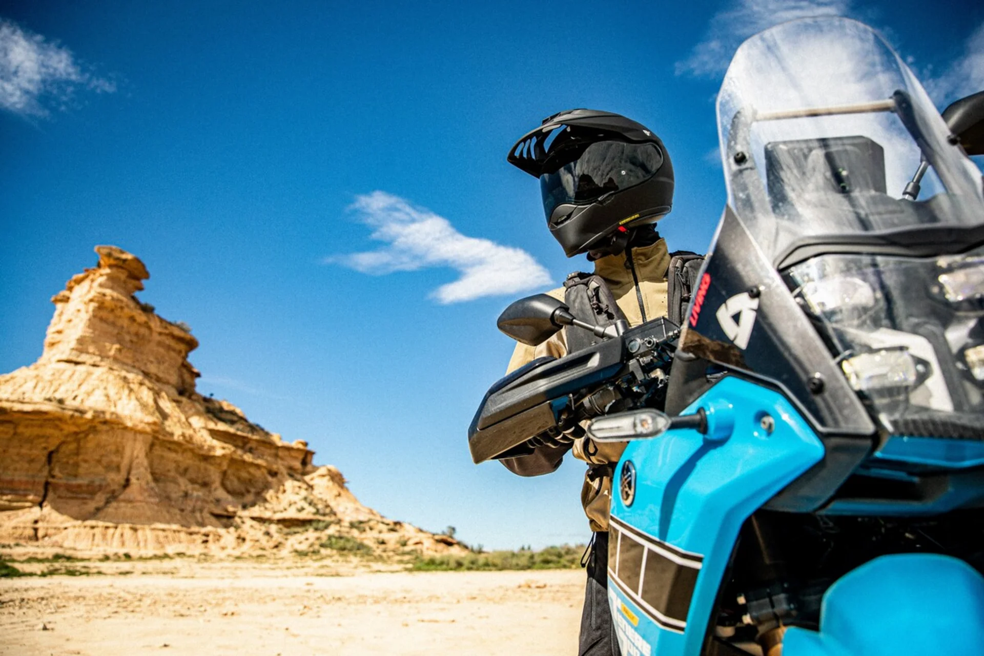 Motorradurlaub © SHOEI Motorradfahrer mit Helm und Jacke vor felsiger Wüstenlandschaft unter blauem Himmel
