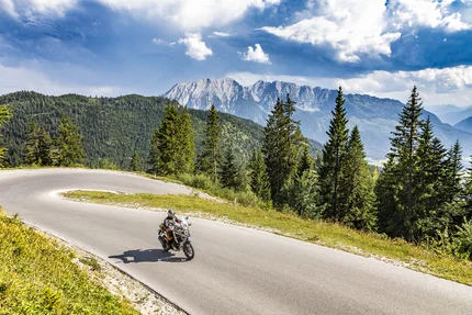 Steiermark © Alexander Seger Motorradfahrer auf kurviger Bergstraße mit Tannen und Bergen im Hintergrund