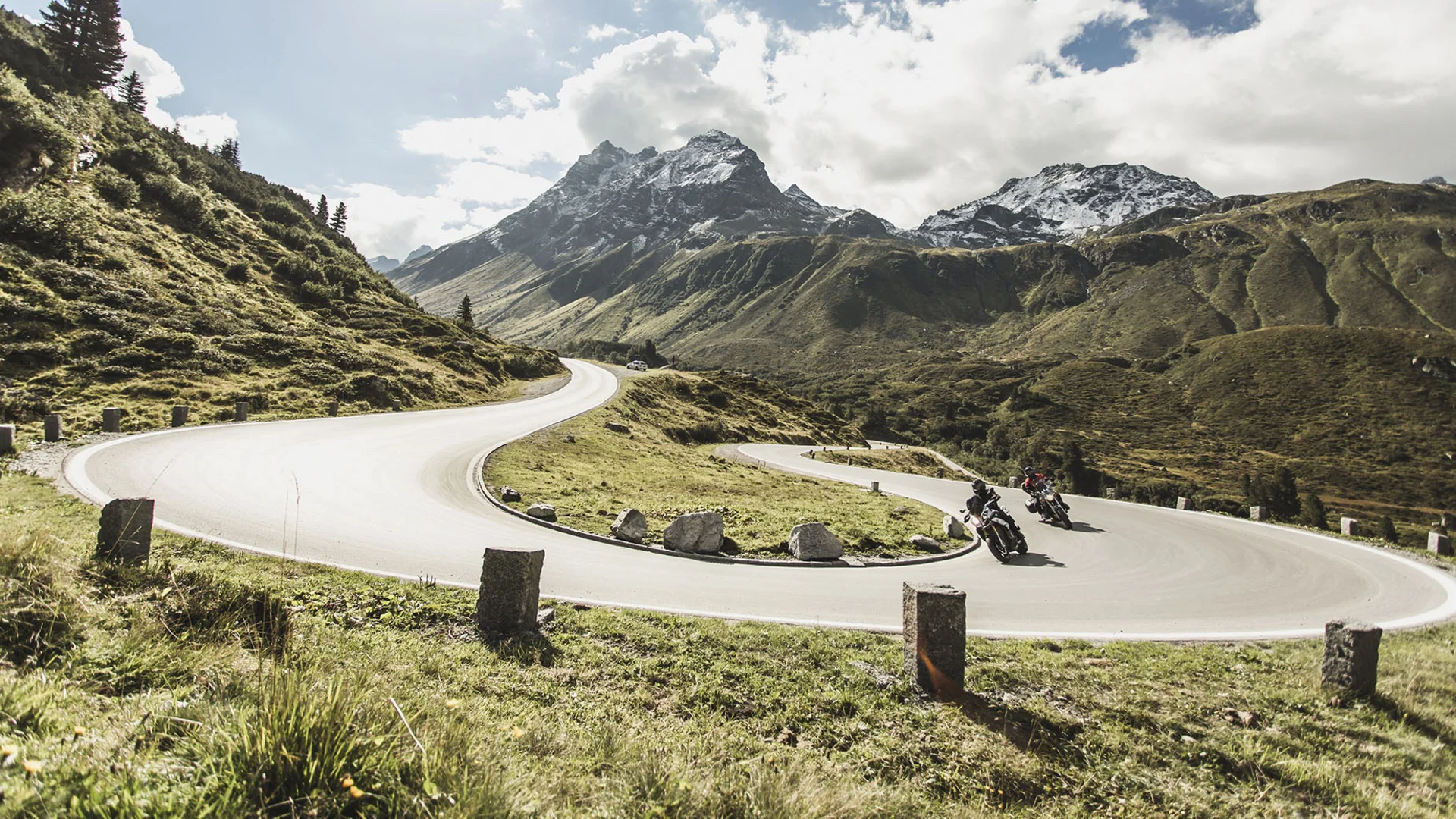 Katalog © Christoph Schöch Motorradfahrer auf kurviger Bergstraße mit schneebedeckten Gipfeln