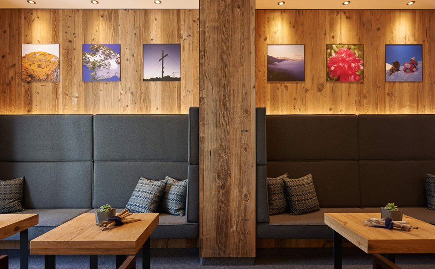 Alpenhotel Laurin ***S © studio22.at - Marcel Hagen Gemütliche Holzwand mit Sitzbereichen und Landschaftsbildern