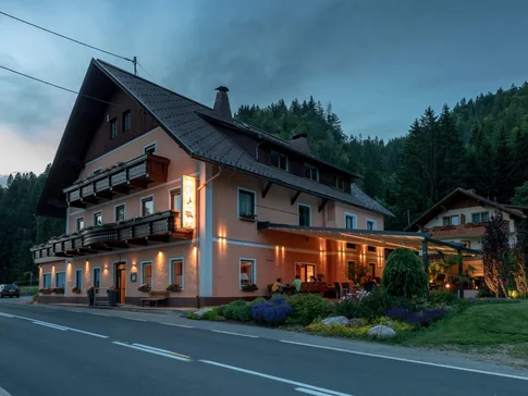 Hotel-Gasthof Strasswirt © Hotel Gasthof Strasswirt Verlicht gastenhuis aan de weg in bosrijk berggebied bij schemering