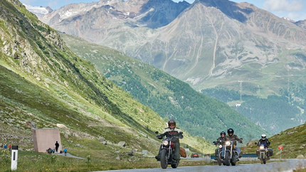 Grenzlandtour Motorradfahrer auf Bergstraße mit Alpen im Hintergrund bei klarem Wetter