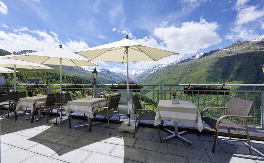 Alpenhotel Laurin ***S © studio22.at - Marcel Hagen Terrasse mit Tischen und Sonnenschirmen vor Bergpanorama