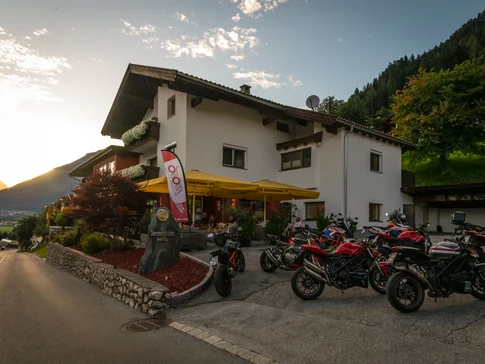 Het Sonnleiten Ski- en Motorhotel Bruck in het Zillertal © Moppetfoto.de Hotel met motorfietsen geparkeerd bij zonsondergang in de bergen