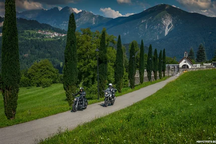 Friaul – Julisch Venetien © Moppetfoto.de Zwei Motorradfahrer fahren auf einem Weg mit Bäumen und Bergen im Hintergrund