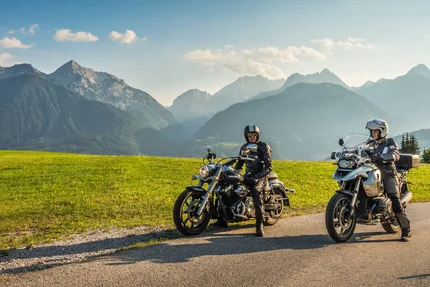 Kärnten © Moppetfoto.de Zwei Motorradfahrer auf Landstraße mit grünen Wiesen und Alpen im Hintergrund