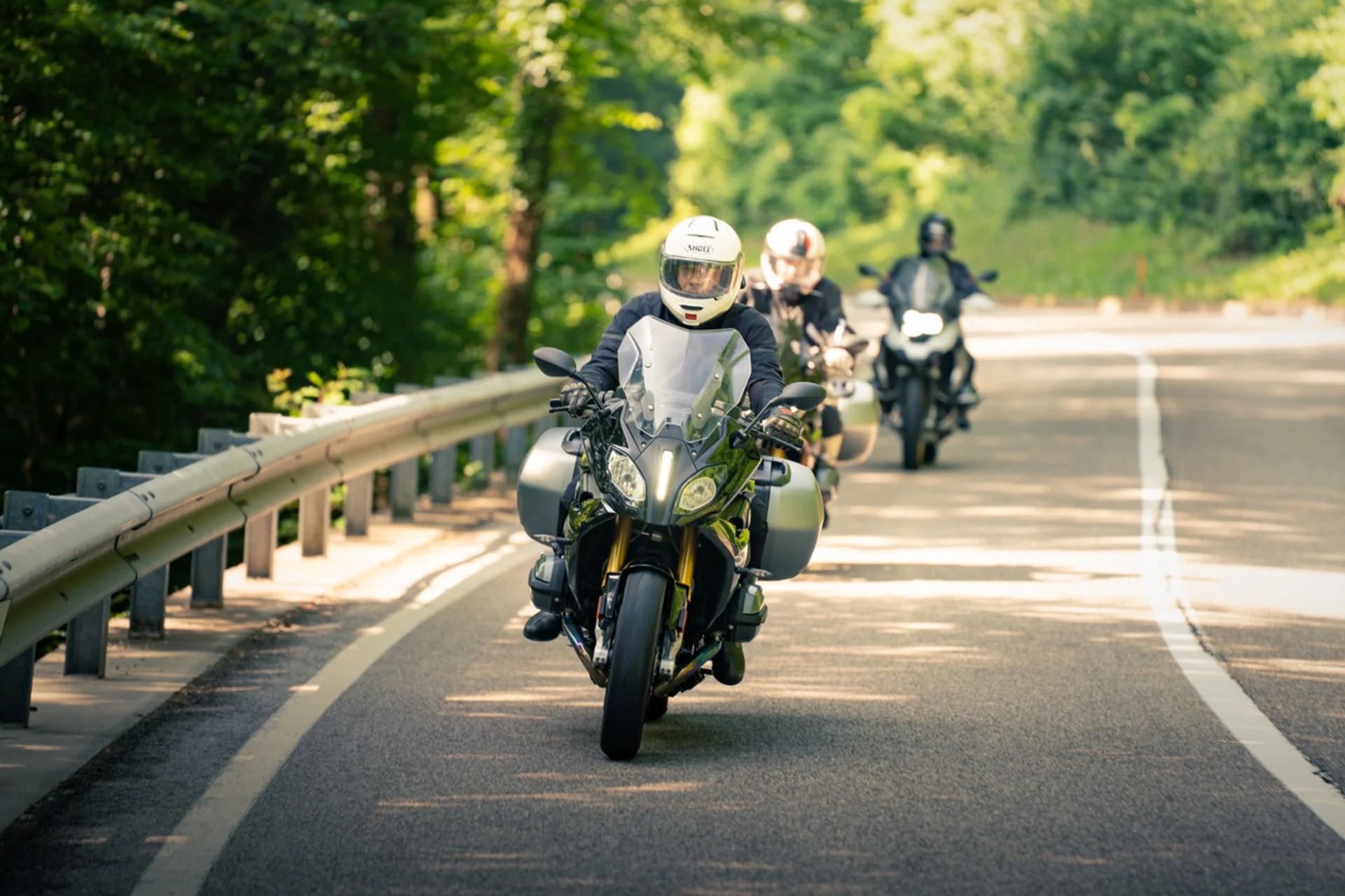 Motorvakantie © Teutschhaus Drie motorrijders op een bochtige weg door het bos
