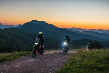 SalzburgerLand © Moppetfoto.de Drei Motorradfahrer fahren auf einem Bergweg bei Sonnenuntergang