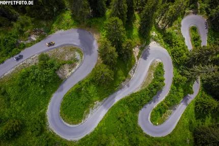 Tirol © Moppetfoto.de Luftaufnahme einer kurvigen Bergstraße mit Motorrädern und grüner Vegetation