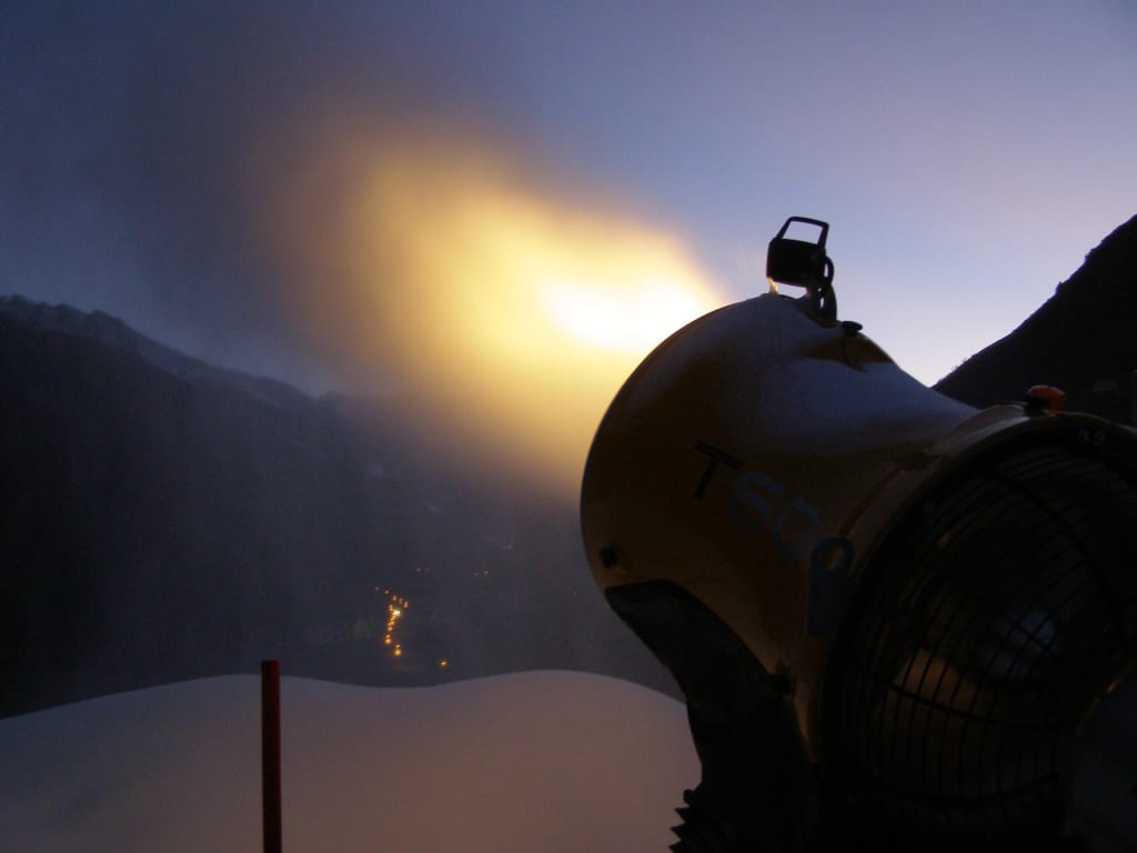 Skiopening 4 Tage - Sonntagsanreise Schneekanone stößt Nebel in verschneiter Berglandschaft aus bei Abendlicht