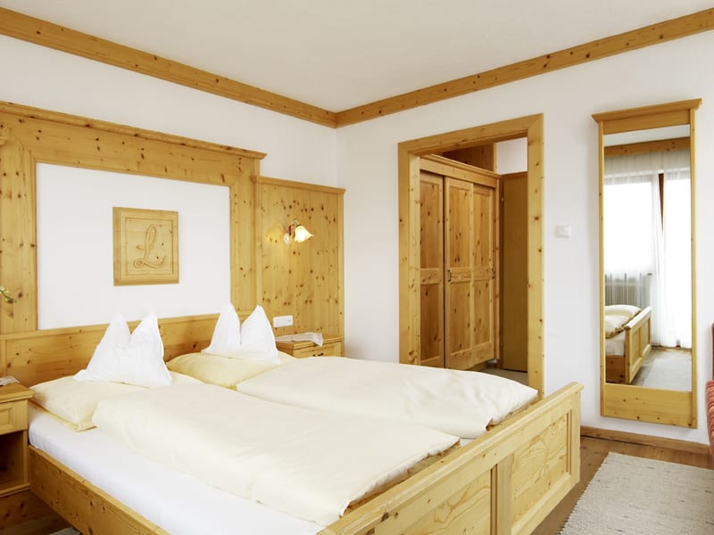 Firn Schnee Pauschale Helles Schlafzimmer mit Holzmöbeln, Doppelbett und großem Spiegel