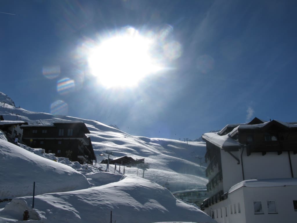 Sonnenschilauf-Pauschale Sonniger Wintertag mit schneebedeckten Hütten in den Bergen