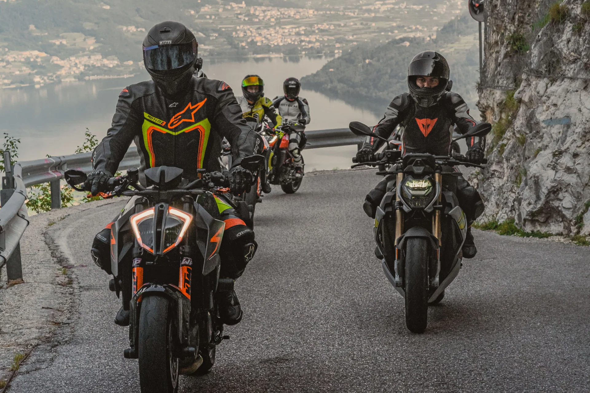 Motorradurlaub © Andrea Acler Vier Motorradfahrer fahren auf bergiger Straße mit Seeblick