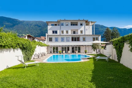 Hotel Teutschhaus © Ingrid Heiss White house with swimming pool and garden in front of mountains under blue sky