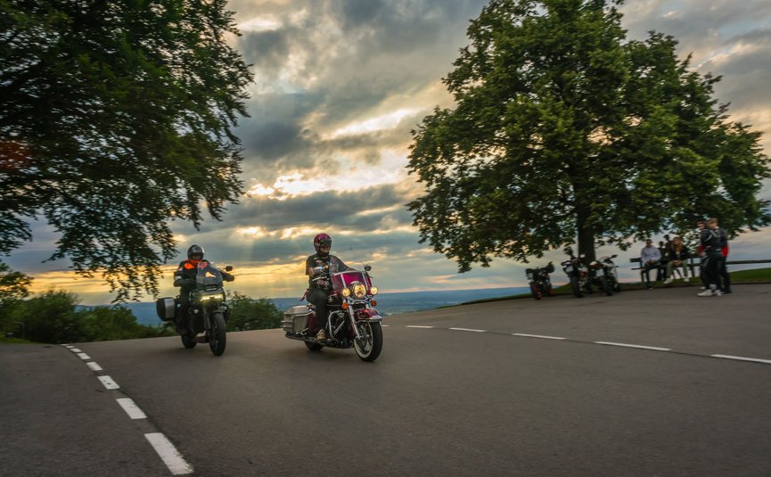 Motorvakantie in Beieren © Moppetfoto.de Twee motorrijders rijden bij zonsondergang een bocht voorbij.