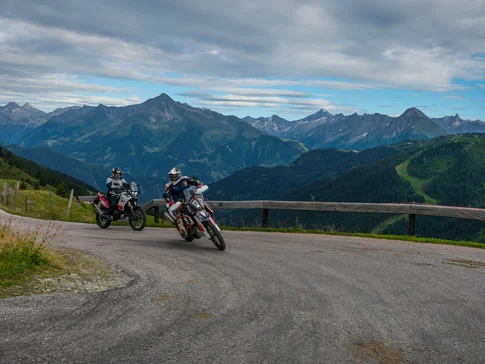 Zillertal - Gerlos Alpine Road Two motorcyclists riding on a mountain road with Alps in the background