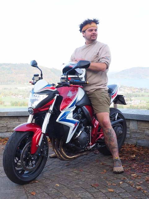 Motorradurlaub © Gast-Hof-Laden Schneeweiss Mann lehnt an rotem Motorrad mit Bergpanorama im Hintergrund