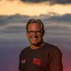 Motorradurlaub © Moppetfoto.de Mann in schwarzem T-Shirt lächelt vor Sonnenuntergang mit rotem Himmel