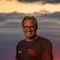Motorradurlaub © Moppetfoto.de Mann in schwarzem T-Shirt lächelt vor Sonnenuntergang mit rotem Himmel