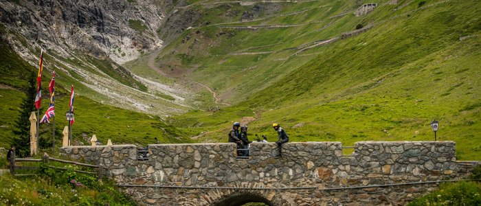 Moto Fun Anna *** © Moppetfoto.de Motorcyclists on stone bridge with winding mountain road in background