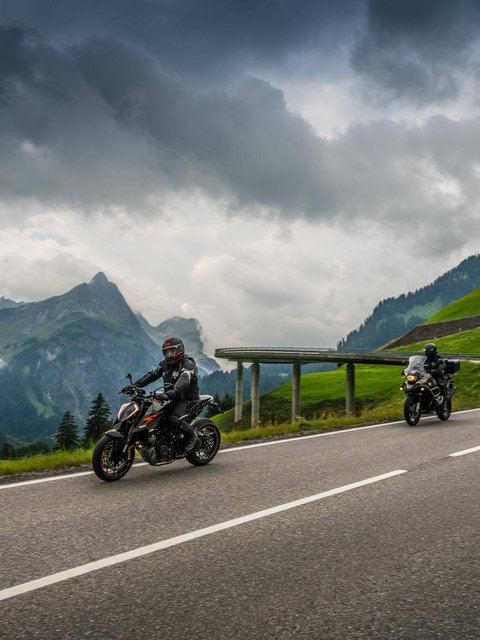 Motorradurlaub © Moppetfoto.de Zwei Motorräder auf bergiger Straße unter bewölktem Himmel