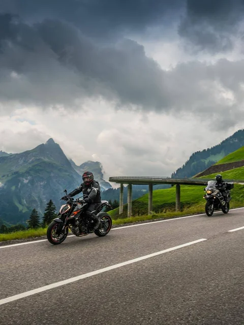 Motorradurlaub © Moppetfoto.de Zwei Motorräder auf bergiger Straße unter bewölktem Himmel