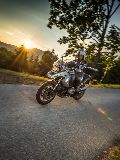 Motorradurlaub © Moppetfoto.de Motorradfahrer auf kurviger Straße bei Sonnenuntergang in ländlicher Umgebung