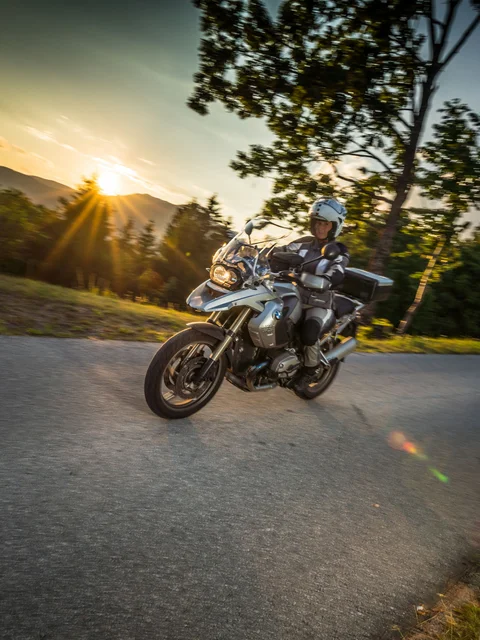 Motorradurlaub © Moppetfoto.de Motorradfahrer auf kurviger Straße bei Sonnenuntergang in ländlicher Umgebung