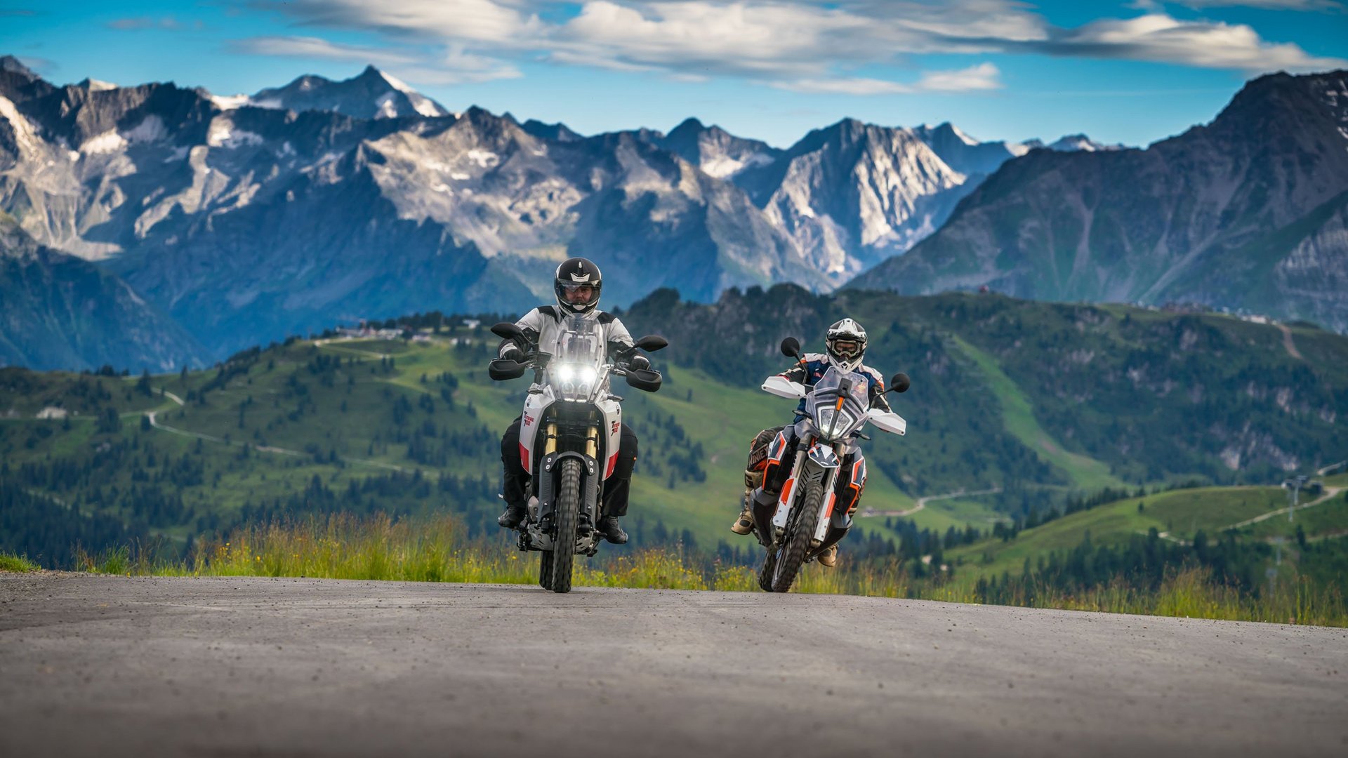 Motorradurlaub © Moppetfoto.de Zwei Motorradfahrer fahren auf Bergstraße mit Alpen im Hintergrund