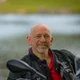 Motorradurlaub © Moppetfoto.de Lächelnder Mann in Motorradjacke mit See im Hintergrund