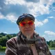 Motorradurlaub © Moppetfoto.de Mann mit roter Sonnenbrille vor Fluss und blauem Himmel