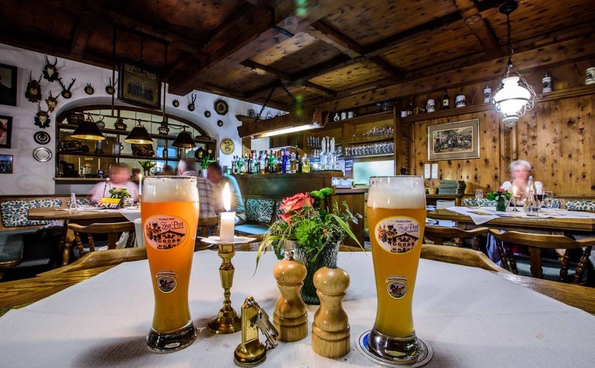 Gasthof Hotel Zur Post Samerberg *** © Team F8 Zwei Biergläser und Kerze in rustikalem Gastraum mit Holzdach