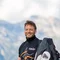 Motorradurlaub © Arik Oberrauch Mann steht neben rotem Motorrad auf Bergstraße mit Berglandschaft im Hintergrund