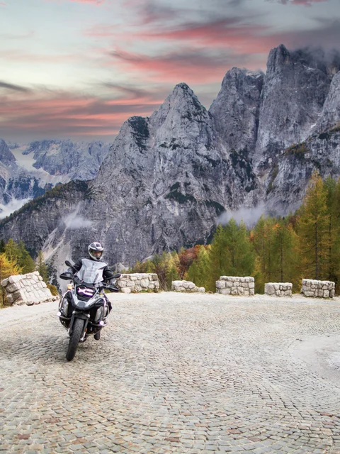 Motorradurlaub © Hotel Grof Motorradfahrer auf kurviger Bergstraße vor Felsgipfeln und herbstlichen Bäumen
