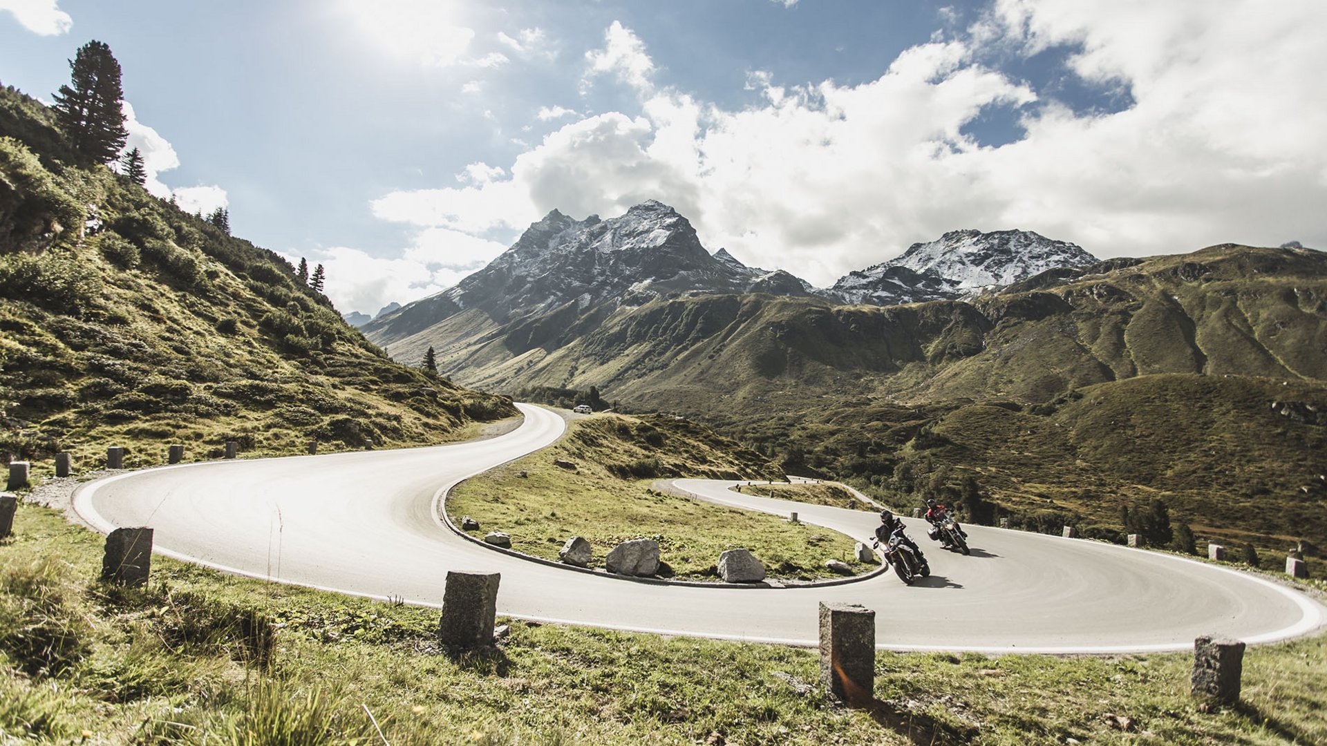 Motorradurlaub © Christoph Schöch Motorradfahrer auf kurviger Bergstraße mit schneebedeckten Gipfeln