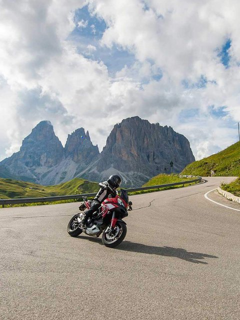 Motorradurlaub © Arik Oberrauch Motorradfahrer auf Bergstraße mit Felsen und bewölktem Himmel