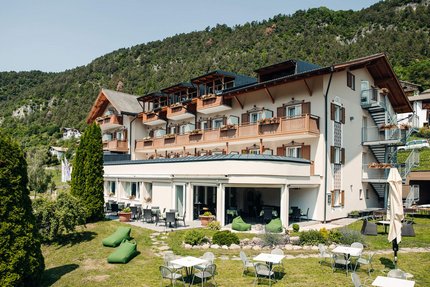 Motorrad-Hotel-Südtirol Ludwigshof © Ivan Bortondello Hotelgebäude mit Terrasse, Gartenmöbeln und Bergen im Hintergrund
