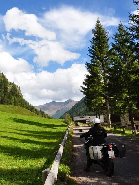 Motorradurlaub © Marisol s.n.c.di Pangrazzi Albino EC Motorradfahrer auf Bergstraße neben grünem Tal und bewaldeten Bergen
