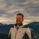 Motorradurlaub © Moppetfoto.de Zwei Motorradfahrer mit ihren Motorrädern vor bergiger Landschaft bei bewölktem Himmel