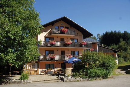 Landhotel Neuhof © Landhotel Neuhof Zenting Drei stöckiges Hotel mit Balkonen und Blumen unter blauem Himmel