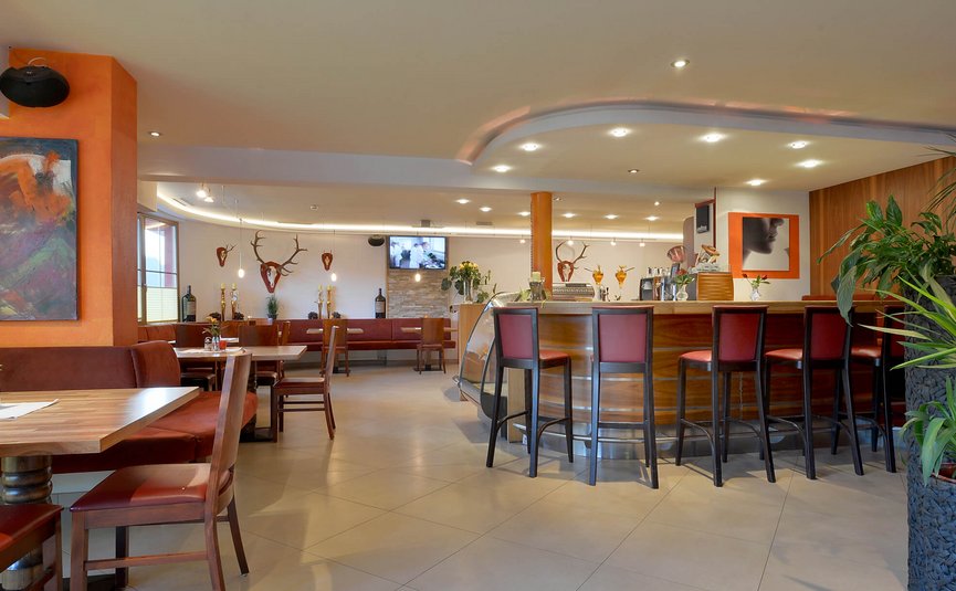Hotel Sonnleiten *** Modern restaurant interior with bar, wooden furniture, and decorative plants