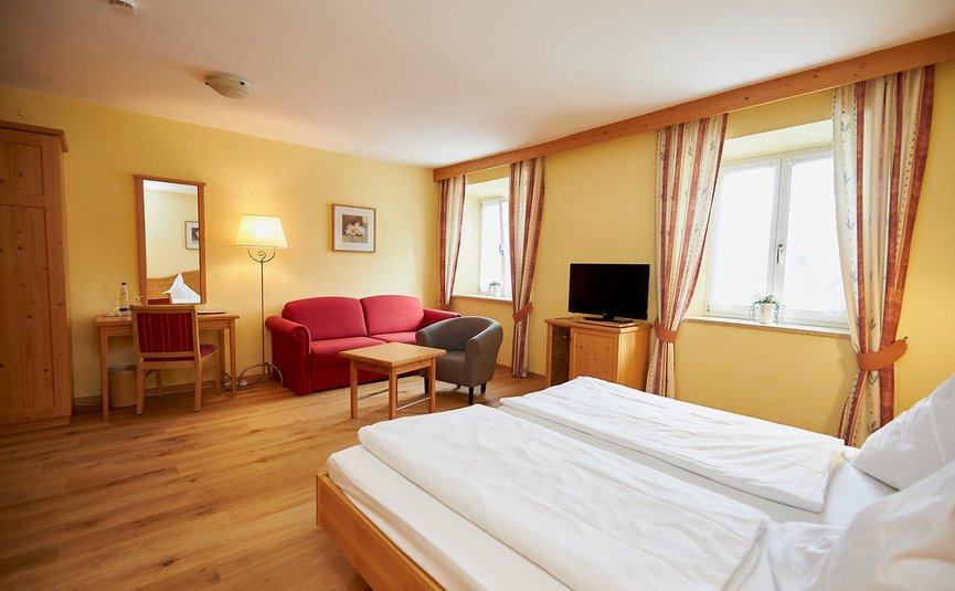 Gasthof Hotel Zur Post Samerberg *** © Team F8 Helles Hotelzimmer mit Doppelbett, rotem Sofa, Schreibtisch und TV